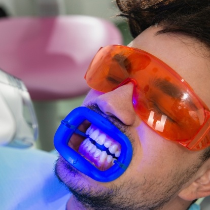 Man getting his teeth professionally whitened in dental chair