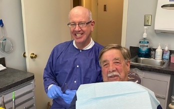 Doctor Lavery smiling next to senior man in dental chair