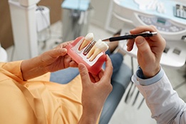 a patient holding a model of a dental implant