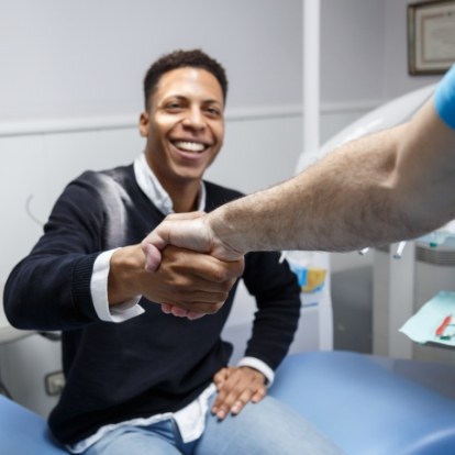 Smiling man shaking hands with his dentist