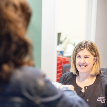 Dental team member smiling at a patient at front desk