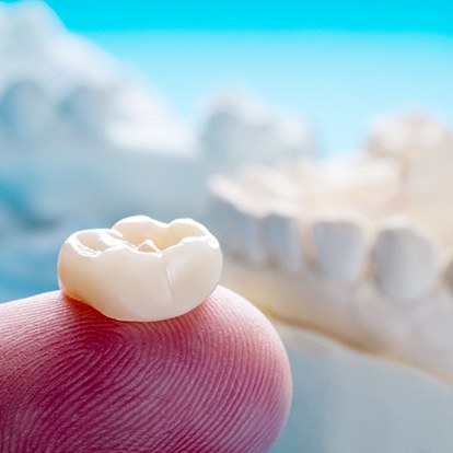A closeup of a ceramic dental crown on a person’s finger