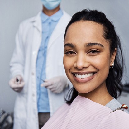 A smiling young woman and her dentist in the background