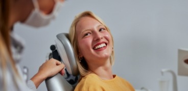 Woman in yellow sweater smiling at her dentist