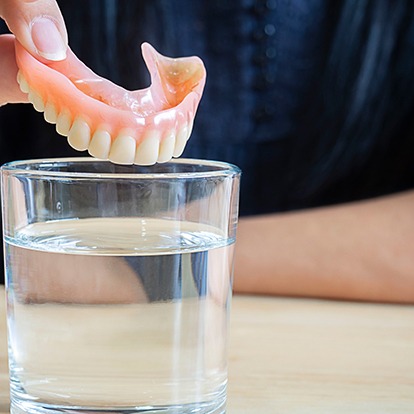 a closeup of a patient holding her dentures
