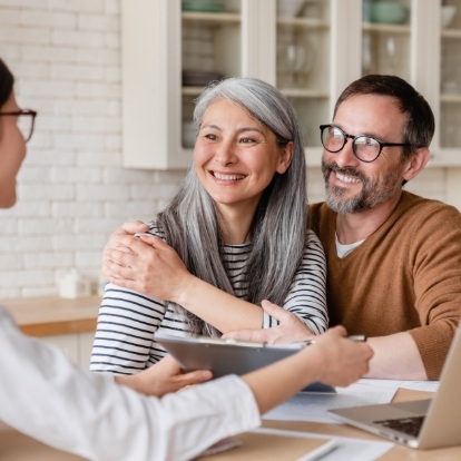 Man and woman smiling at person sitting across table