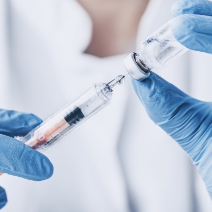 Dentist drawing syringe from vial of clear liquid