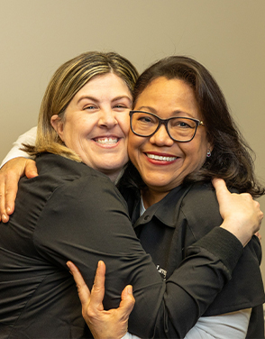 Two dental team members smiling and hugging