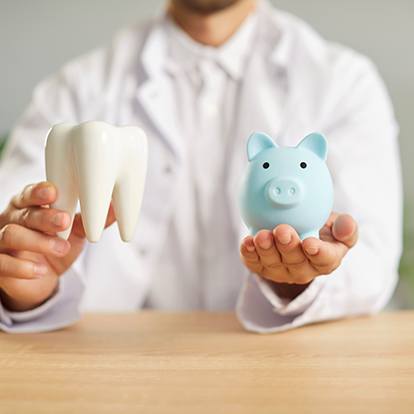 a dentist holding a model tooth and a piggy bank