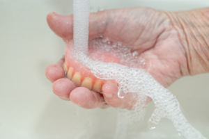 a patient rinsing off their dentures